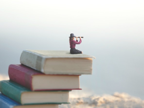 Woman with telescope sat on pile of books